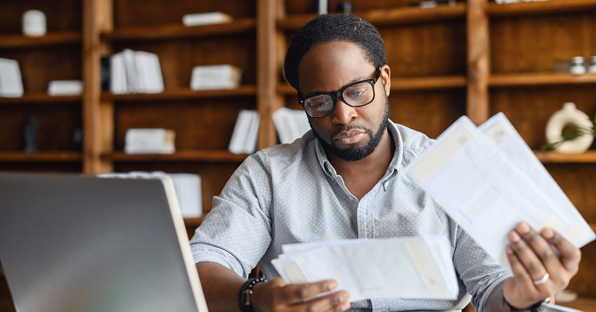 man in home reviewing envelopes and letters